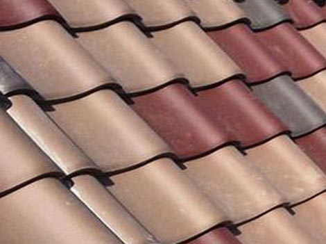 Construction worker uses a power drill to attach a cap the the top of a sheet metal roofing job with screws.